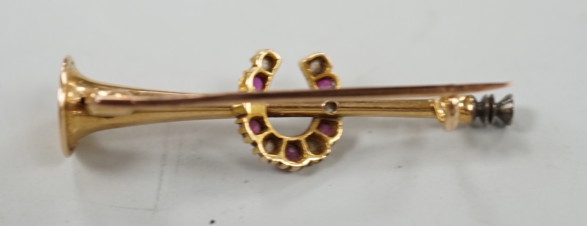An Edwardian yellow metal, ruby and diamond set hunting horn and horseshoe brooch, 37mm, gross weight 2.6 grams.